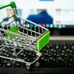 E-commerce shopping cart placed on an open laptop keyboard, symbolizing online retail and digital shopping experiences.
